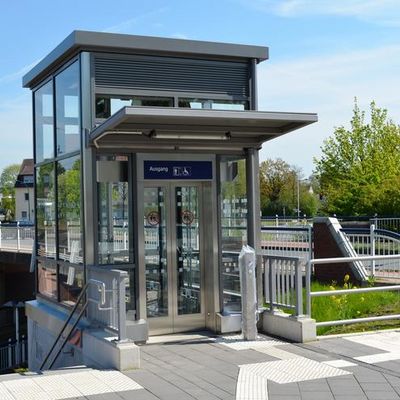 Rechts neben dem Bahnhogfsgebäude steht frei ein Aufzug neben der Straßenbrücke zum Gesundheitszentrum. Der Fahrstuhl besteht aus einer Glas-Metall-Konstruktion. Mit ihm können die Fahrgäste hinunter zur Billerbecker Straße fahren.